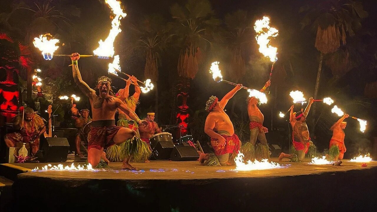 Polynesian fire-knife dancers performing at a Kauai luau at night